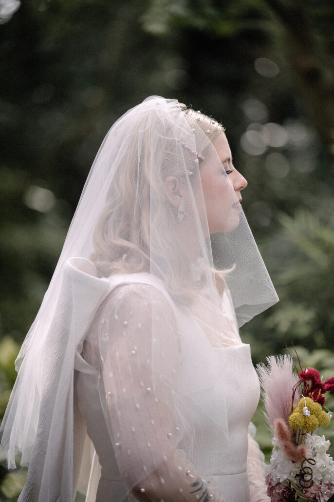 The bride in her veil with eyes closed, holding the bouquet she made at home with her mother for her elopement in Japan.