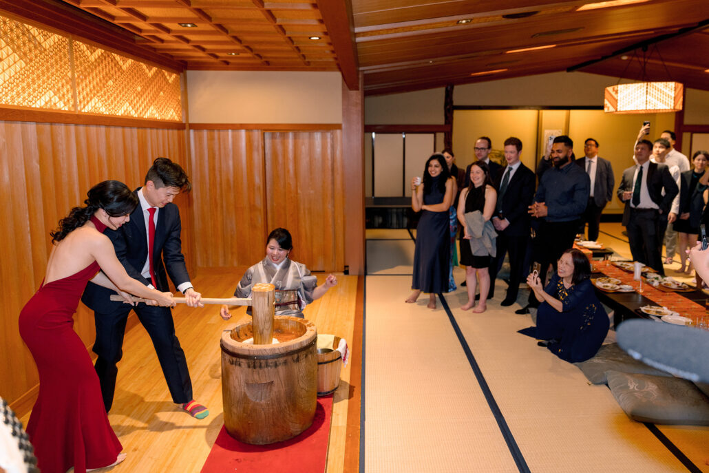 At their welcome dinner the night before the wedding, the couple pound mochi as a woman in kimono turns the rice and guests watch from the tatami.